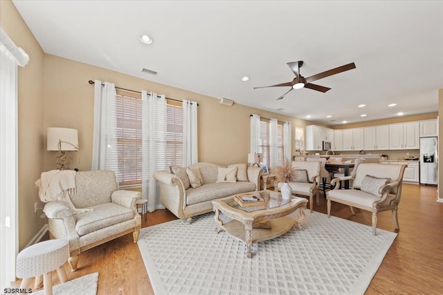 living room featuring a ceiling fan, recessed lighting, visible vents, and light wood-style floors