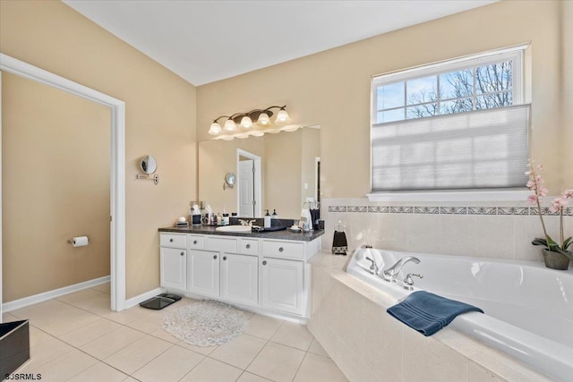 bathroom with a garden tub, tile patterned flooring, baseboards, and vanity