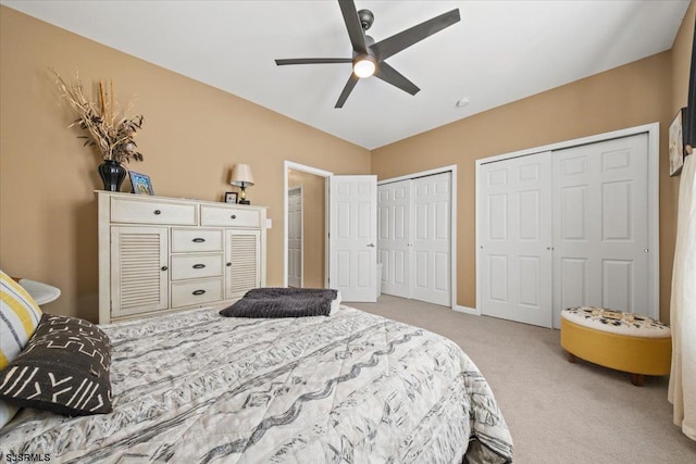 bedroom featuring ceiling fan, baseboards, carpet flooring, and multiple closets