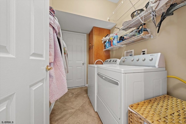 clothes washing area with light tile patterned floors, washer and clothes dryer, and cabinet space