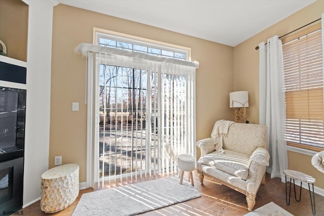 living area featuring baseboards, wood finished floors, and a healthy amount of sunlight