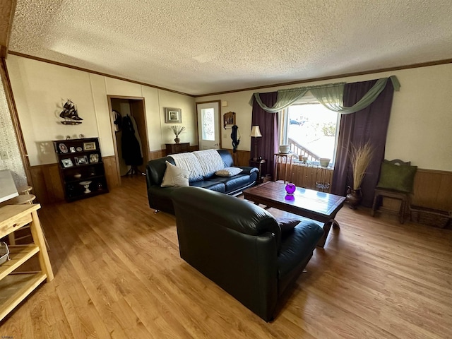 living room with ornamental molding, hardwood / wood-style floors, a textured ceiling, and wood walls