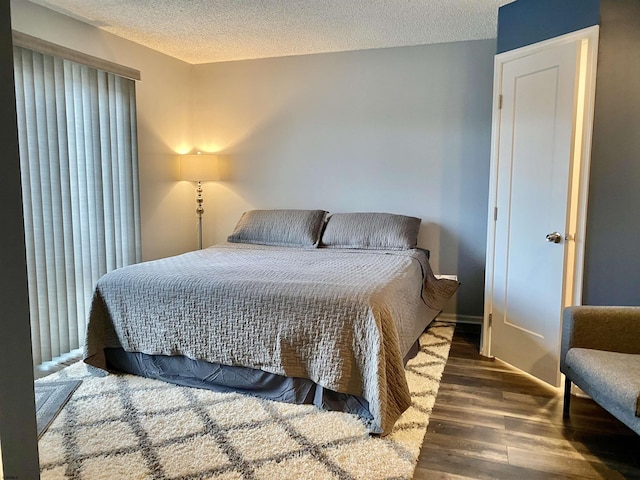 bedroom with dark hardwood / wood-style floors and a textured ceiling