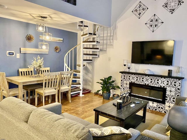 living room with a tiled fireplace, wood-type flooring, and ornamental molding