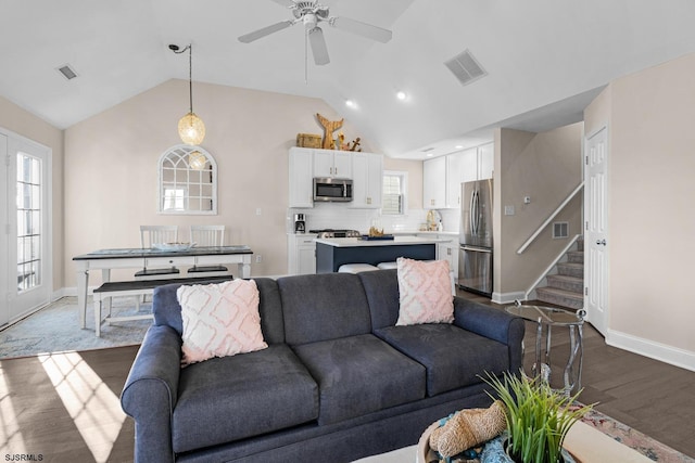 living room featuring ceiling fan, dark hardwood / wood-style floors, and vaulted ceiling