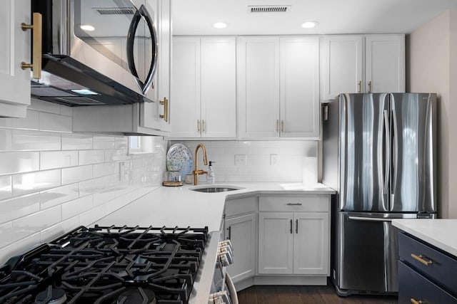 kitchen with tasteful backsplash, sink, white cabinetry, and stainless steel appliances