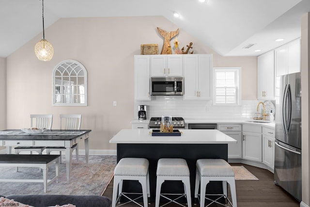 kitchen featuring lofted ceiling, hanging light fixtures, stainless steel appliances, and sink