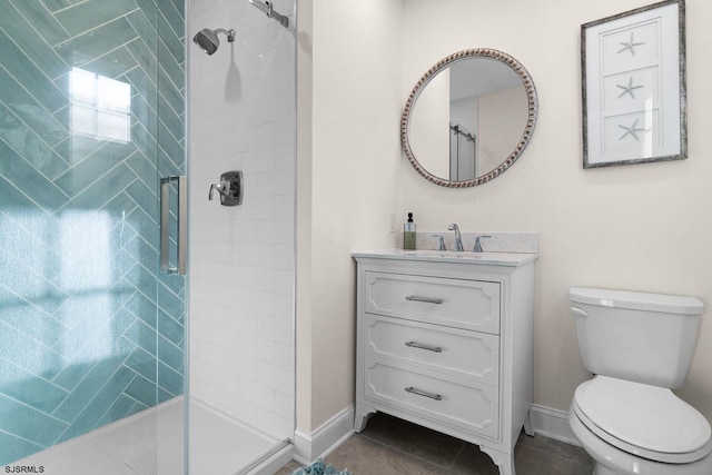 bathroom featuring vanity, a tile shower, tile patterned floors, and toilet