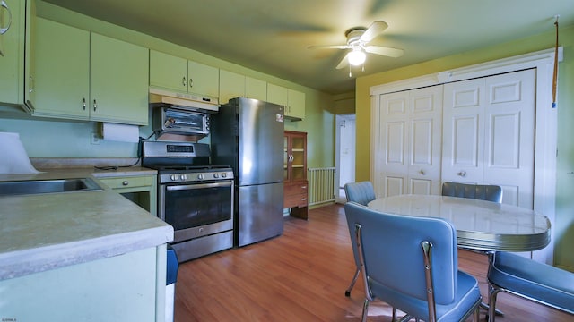 kitchen with sink, green cabinetry, appliances with stainless steel finishes, ceiling fan, and hardwood / wood-style floors