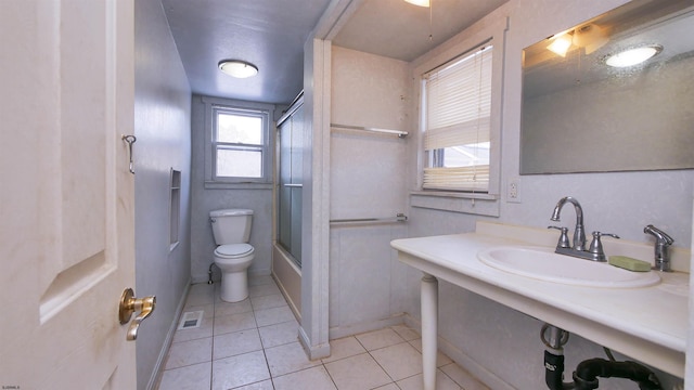 full bathroom featuring toilet, tile patterned floors, bath / shower combo with glass door, and sink