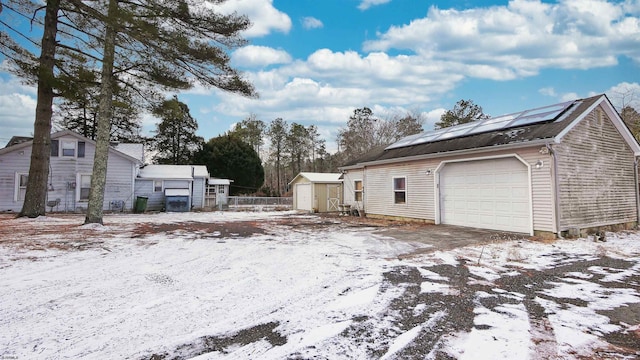 snow covered property with a shed and solar panels