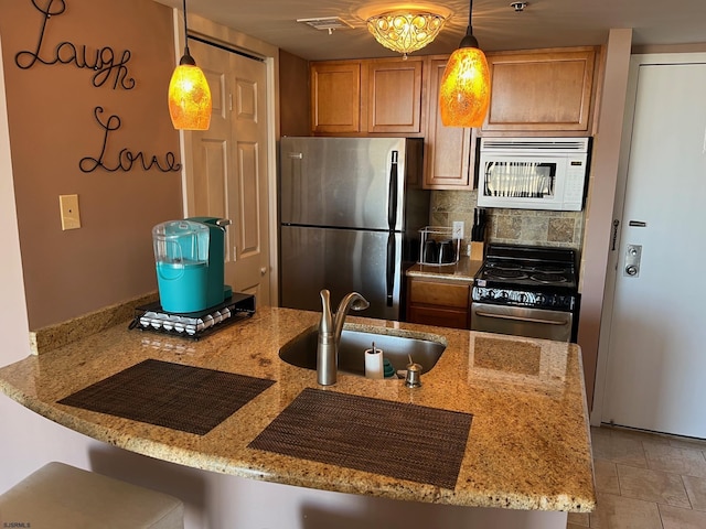 kitchen with pendant lighting, sink, kitchen peninsula, and appliances with stainless steel finishes