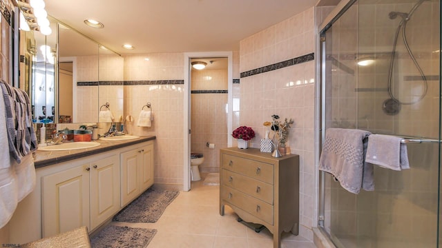 bathroom with toilet, an enclosed shower, tile walls, vanity, and tile patterned flooring