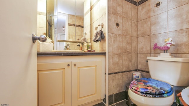 bathroom featuring vanity, toilet, and tile walls