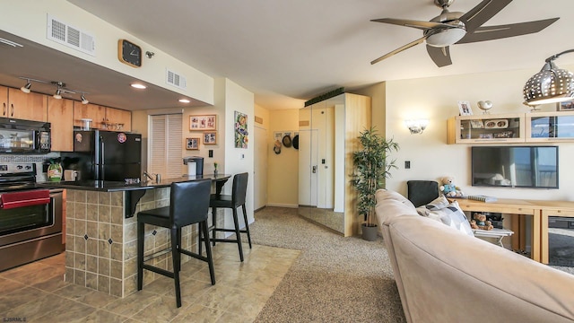 kitchen with a breakfast bar area, ceiling fan, carpet flooring, black appliances, and kitchen peninsula