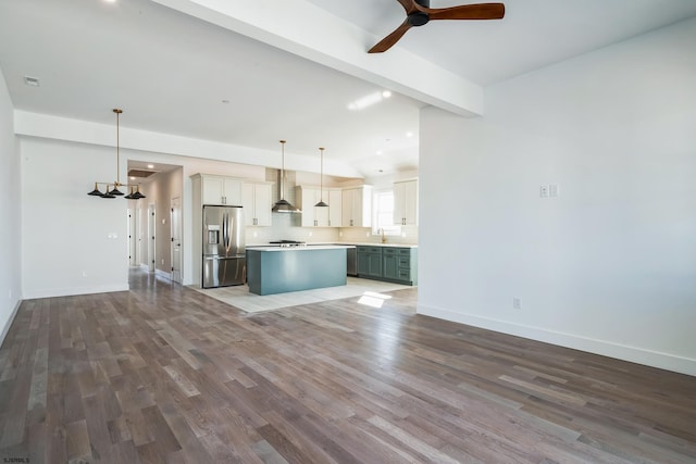 kitchen with stainless steel appliances, white cabinets, a kitchen island, decorative light fixtures, and wall chimney exhaust hood