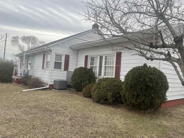 view of side of property with central AC unit and a lawn