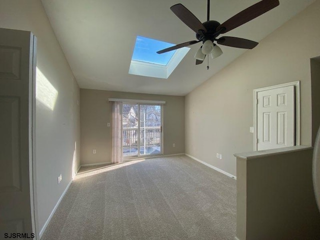 carpeted empty room featuring ceiling fan and vaulted ceiling with skylight