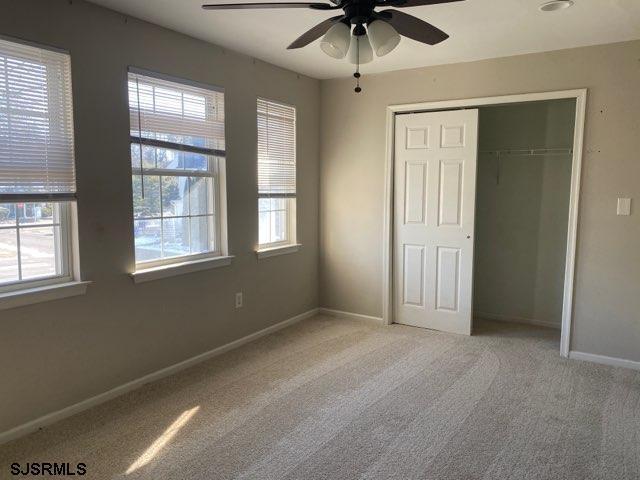 unfurnished bedroom with light carpet, a closet, and ceiling fan