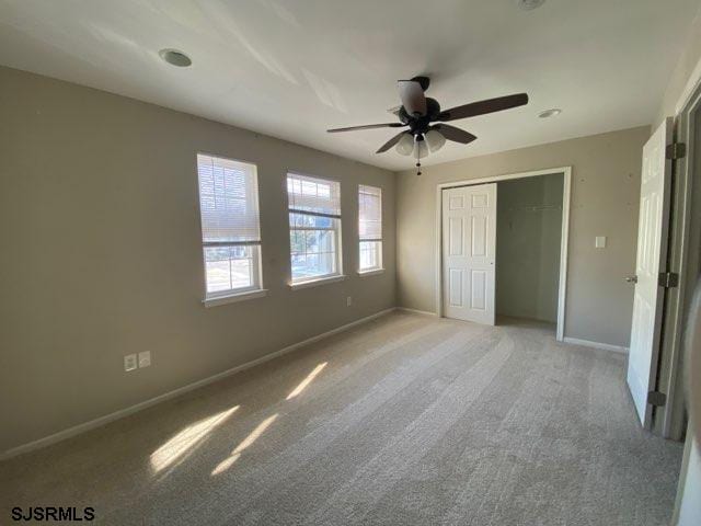 unfurnished bedroom with light carpet, a closet, and ceiling fan