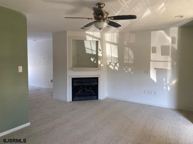 unfurnished living room featuring ceiling fan and carpet