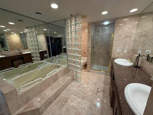 full bathroom featuring vanity, tile walls, shower with separate bathtub, and toilet