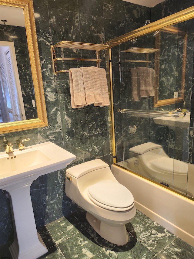 bathroom with tile walls, enclosed tub / shower combo, and toilet