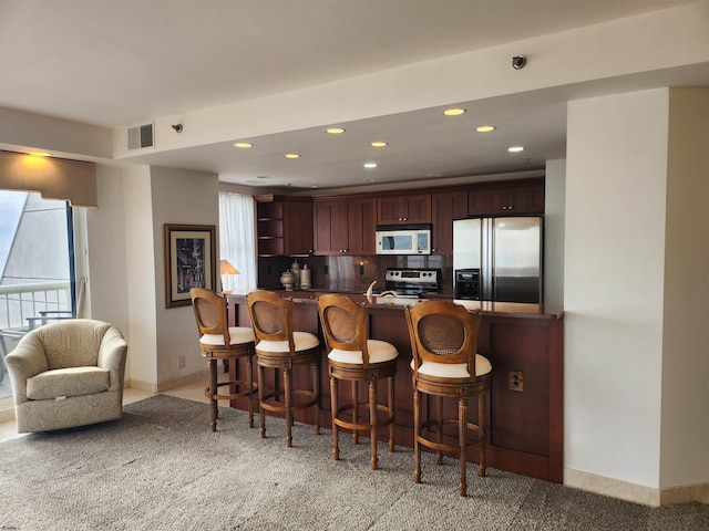 kitchen featuring a healthy amount of sunlight, appliances with stainless steel finishes, kitchen peninsula, and decorative backsplash