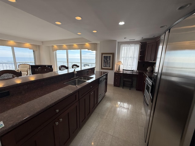 kitchen with sink, a water view, dark stone counters, and appliances with stainless steel finishes