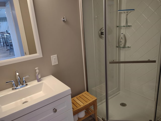 bathroom featuring a shower with door and vanity