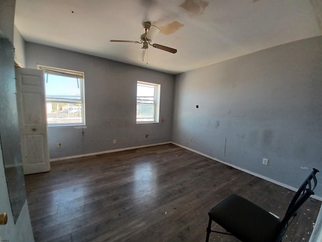 empty room featuring dark wood-type flooring and ceiling fan