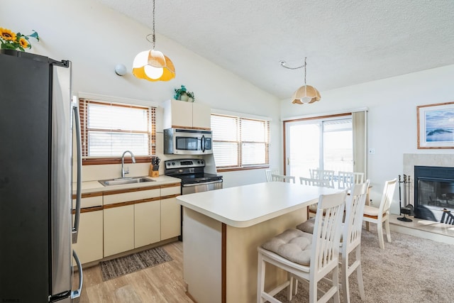 kitchen featuring sink, a center island, vaulted ceiling, hanging light fixtures, and stainless steel appliances