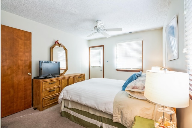 bedroom featuring a textured ceiling, light colored carpet, and ceiling fan