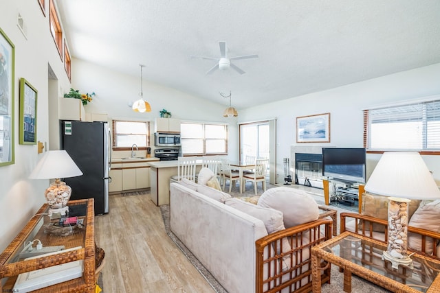 living room featuring lofted ceiling, sink, a textured ceiling, ceiling fan, and light hardwood / wood-style floors