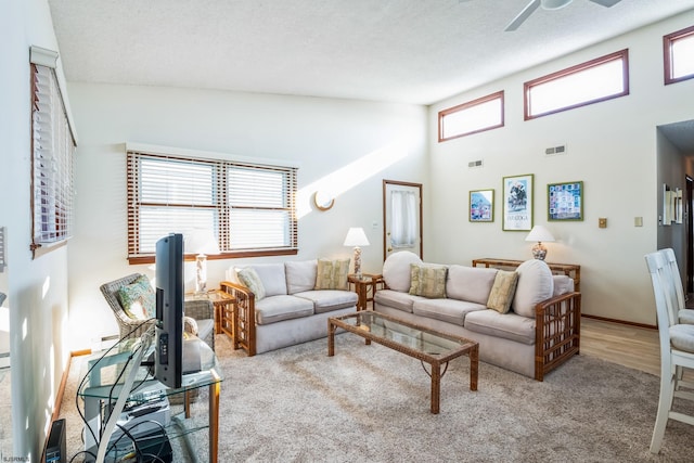 living room featuring a high ceiling, light colored carpet, a textured ceiling, and ceiling fan