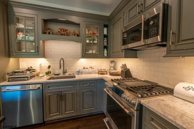 kitchen featuring stainless steel appliances, tasteful backsplash, light stone countertops, and sink