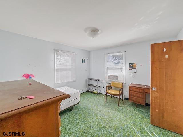 sitting room featuring carpet floors, a baseboard heating unit, and a wealth of natural light