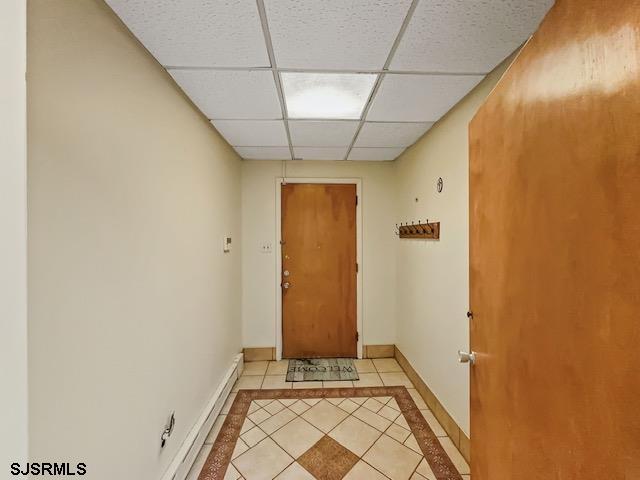 doorway to outside featuring a paneled ceiling and light tile patterned flooring