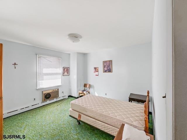 carpeted bedroom with a baseboard heating unit