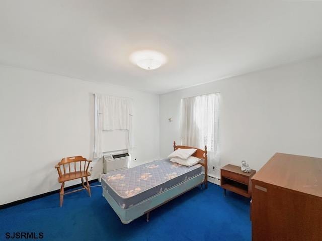 carpeted bedroom with baseboard heating and an AC wall unit