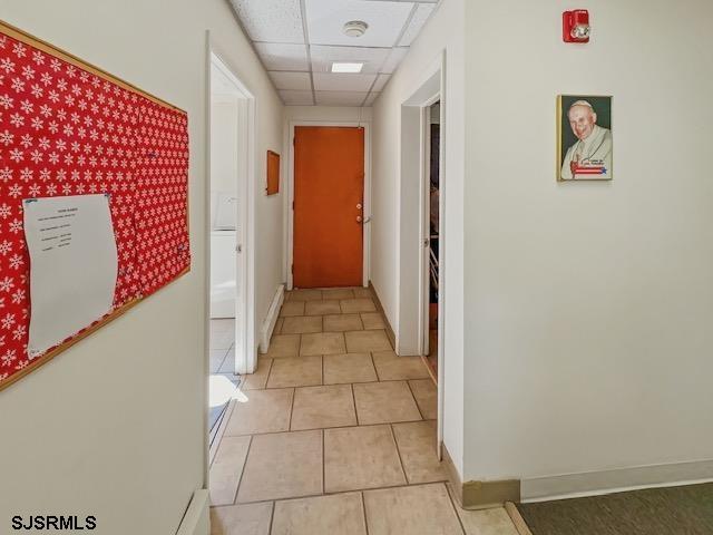 hallway featuring light tile patterned flooring and a drop ceiling