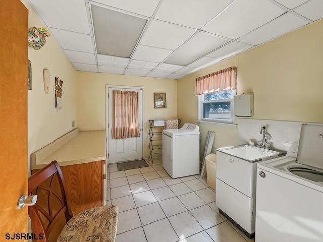 laundry area with separate washer and dryer, sink, and light tile patterned floors