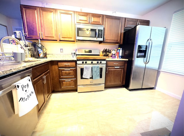 kitchen featuring light stone counters, sink, and stainless steel appliances