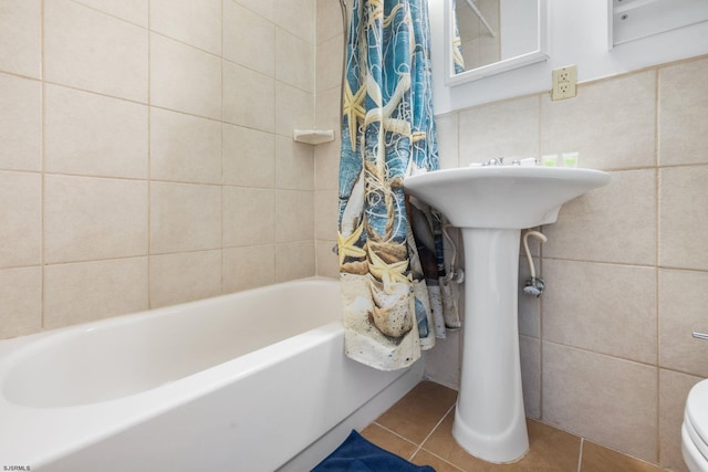 bathroom with shower / bath combo with shower curtain, tile patterned floors, toilet, and tile walls