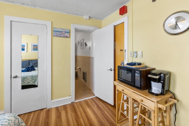 hallway with light wood-type flooring and a textured ceiling