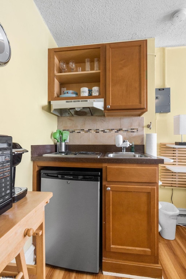 kitchen featuring dishwashing machine, sink, gas stovetop, a textured ceiling, and light wood-type flooring