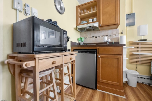 kitchen featuring tasteful backsplash, dishwasher, a breakfast bar area, and light wood-type flooring