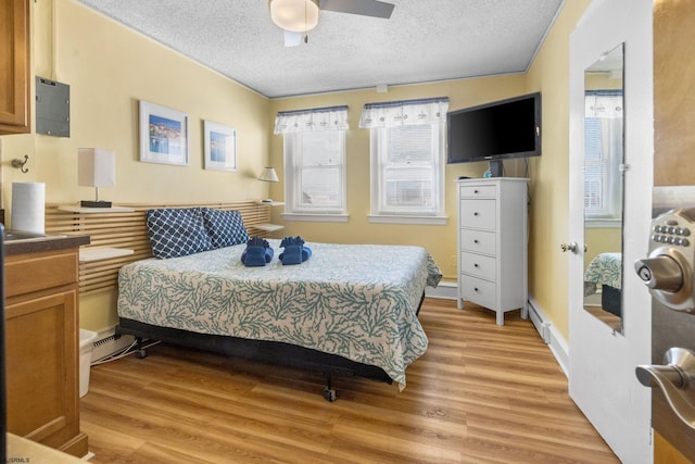 bedroom featuring a baseboard heating unit, a textured ceiling, light hardwood / wood-style floors, and ceiling fan