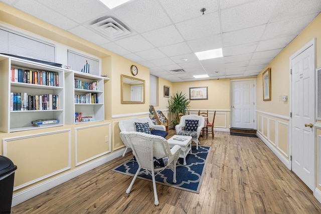 living area featuring a drop ceiling, hardwood / wood-style floors, and built in features