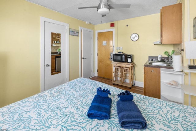 bedroom with wood-type flooring, sink, a textured ceiling, and ceiling fan